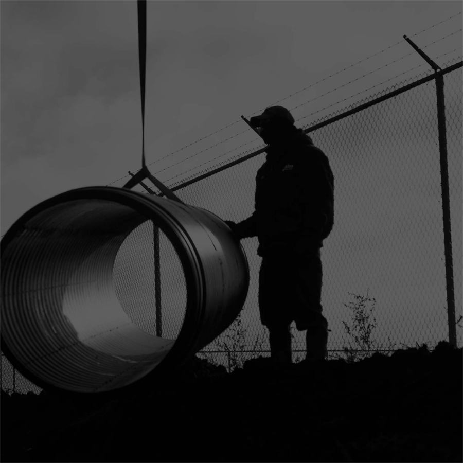 A Fratco worker guiding a large corrugated pipe as it is lifted
